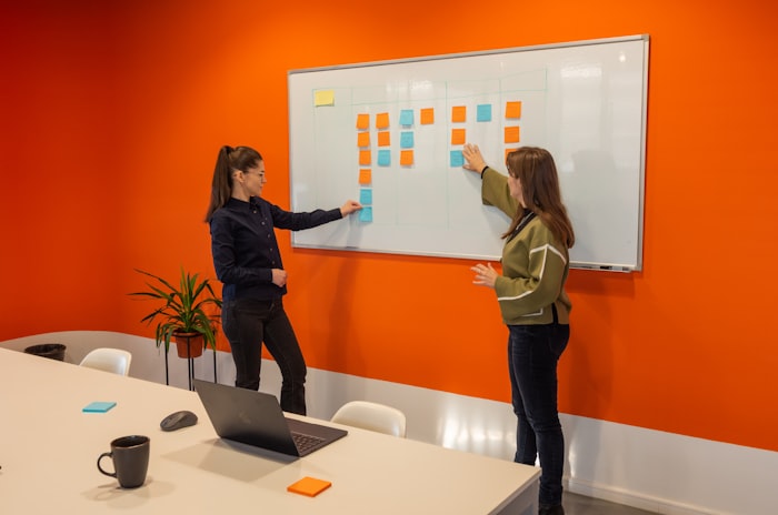 Two colleagues planning with sticky notes on a whiteboard